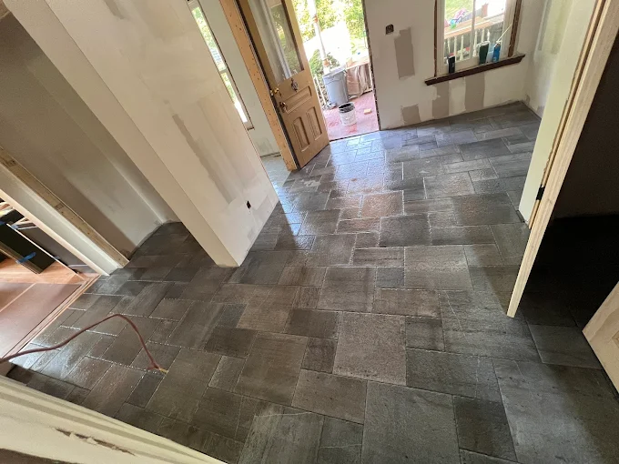 Stone tile floor in entryway with wooden door and natural light