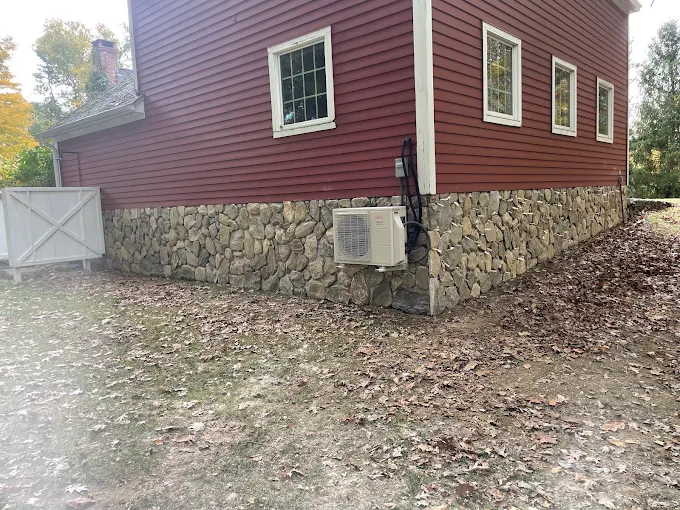 Red house with stone foundation and mini-split air conditioner outside