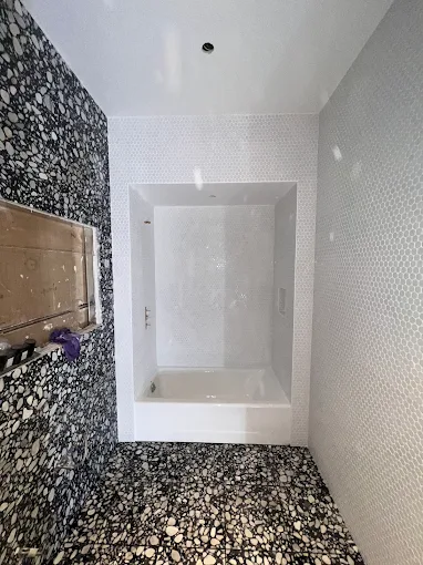 Modern bathroom with stone mosaic walls and white bathtub
