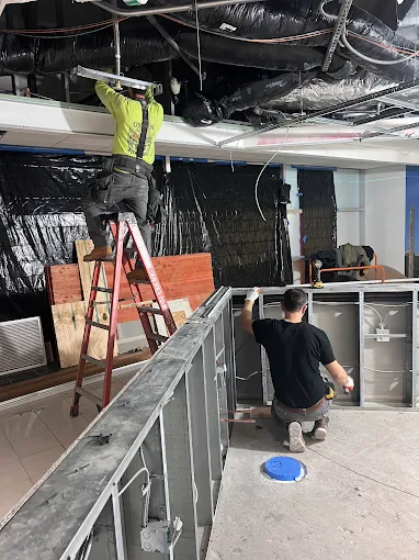 Workers installing insulation and ductwork in a commercial renovation project