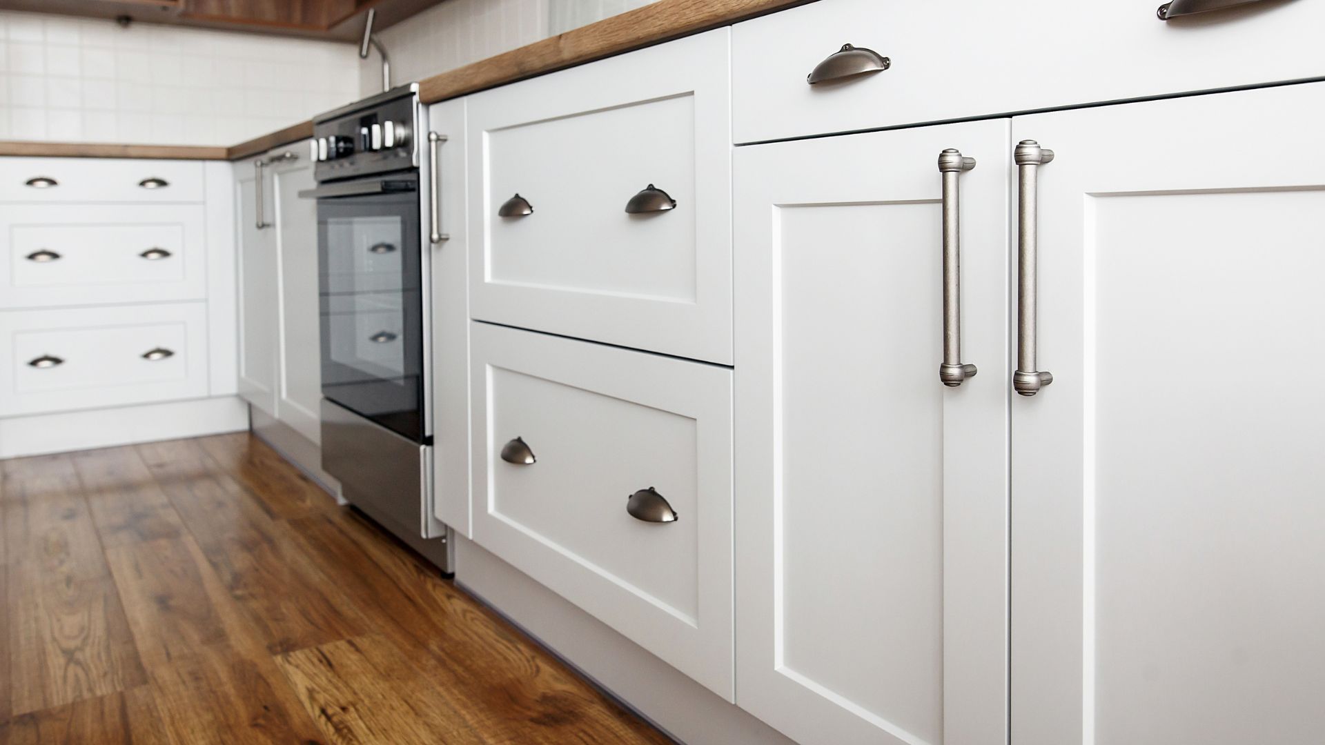 White kitchen cabinets with stainless steel handles and oven