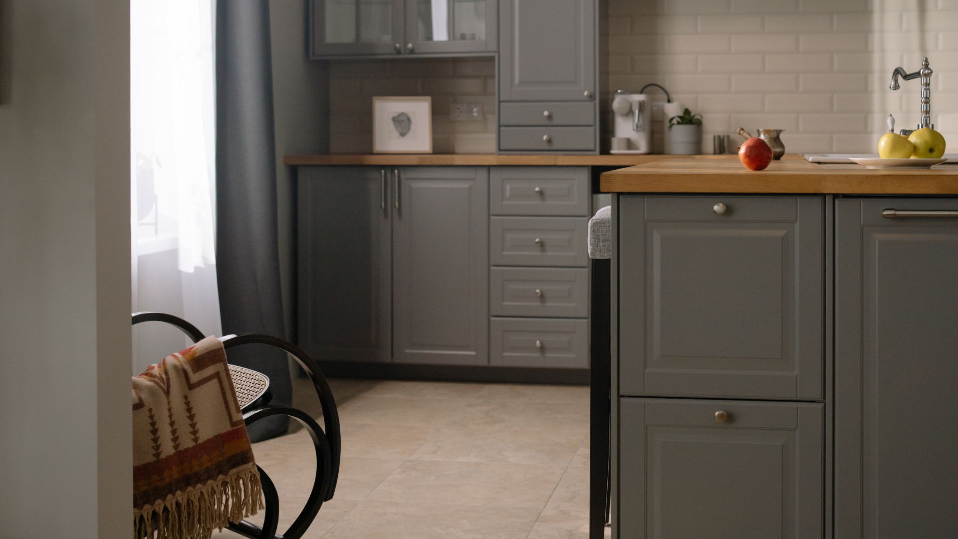 Modern gray kitchen with wooden countertop, fruits, and a cozy blanket