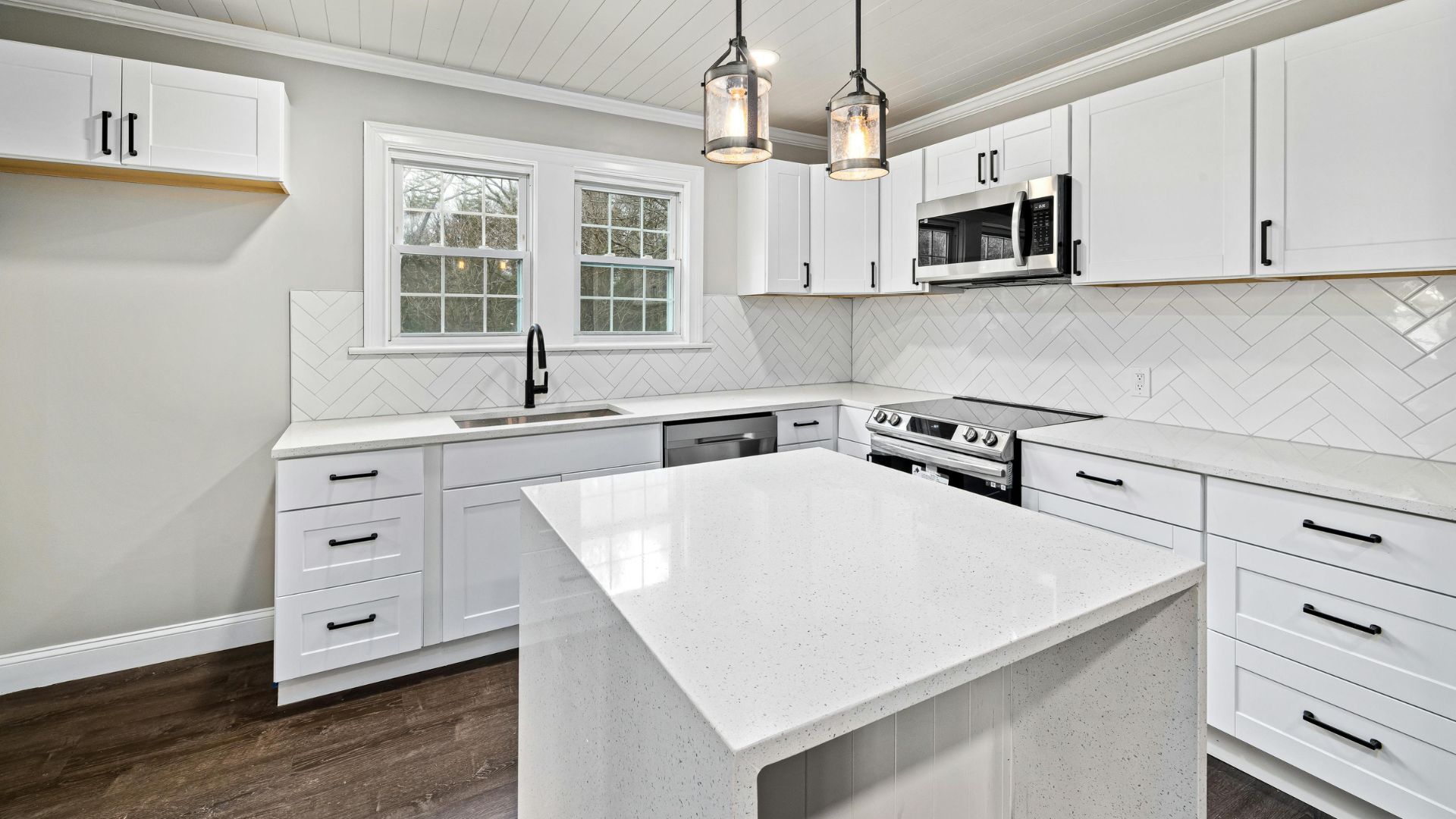 Modern white kitchen with herringbone backsplash and pendant lights