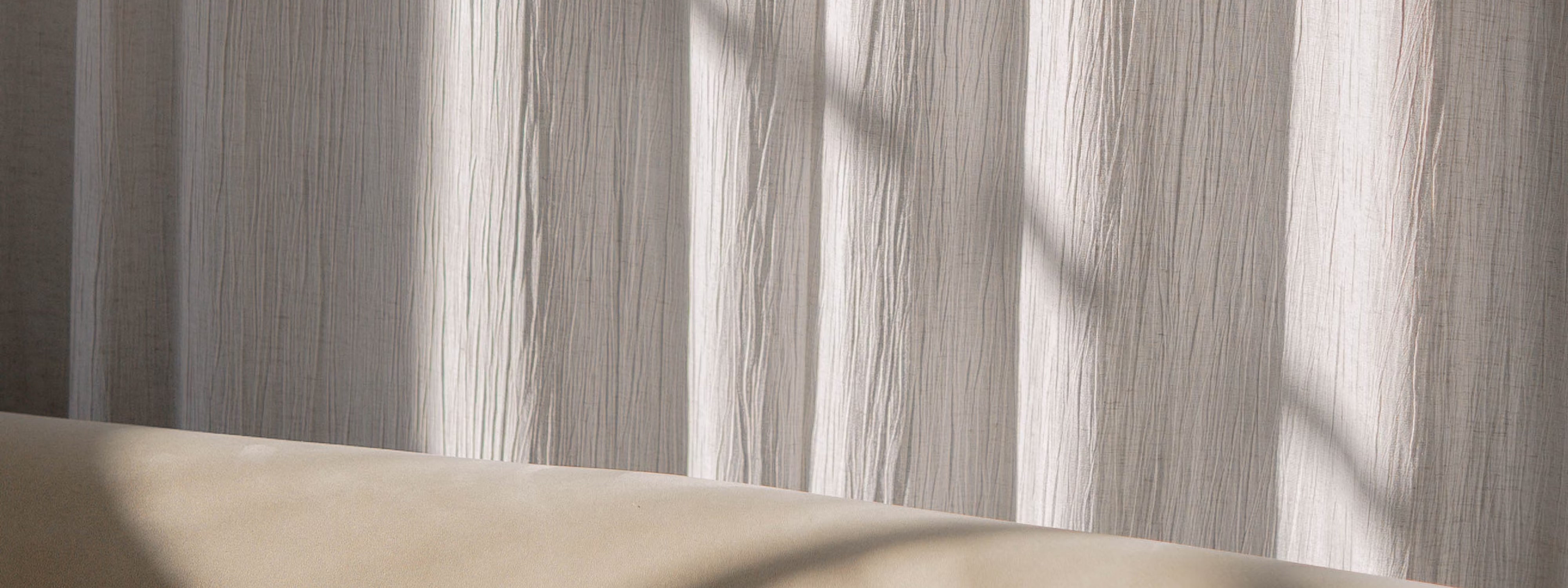 Soft light filtering through textured white curtains, casting gentle shadows