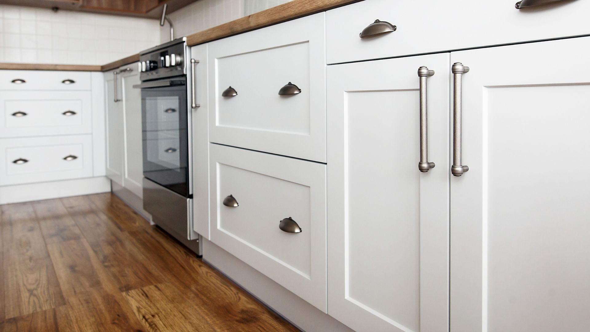 White kitchen cabinets with silver handles and hardwood floor